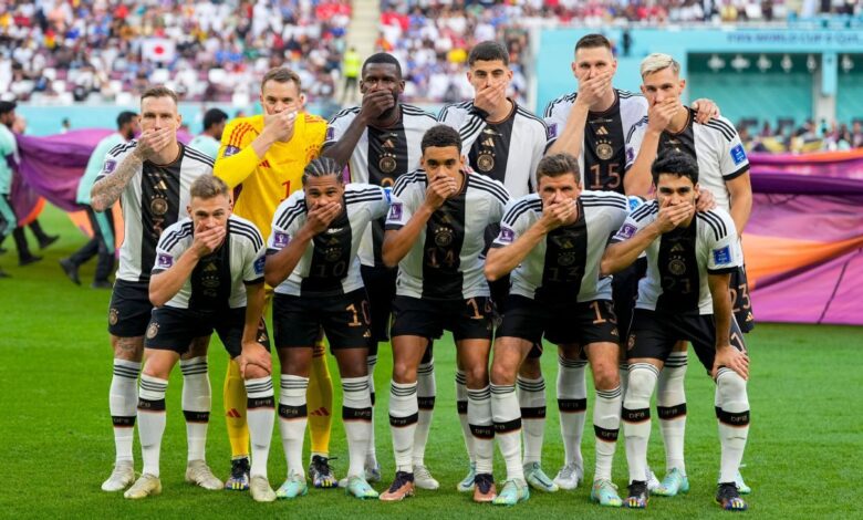 German players cover their mouths in a team photo between OneLove armbands